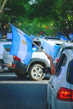 2020-10-12, Mendoza, Argentina: A man holds an argentinian flag from his car during a protest against the national government.