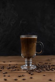Steaming coffee over wooden surface and black background.
