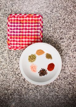 Spices on a dish over a granite countertop. Top down minimalist composition.