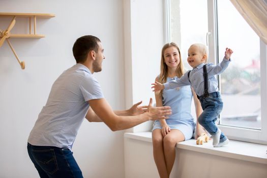 Mom, dad and little son are playing at home. Young family with a child.