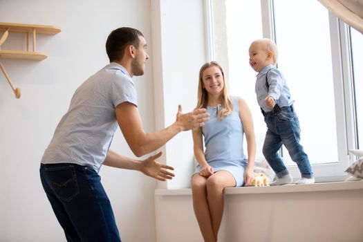 Mom, dad and little son are playing at home. Young family with a child.