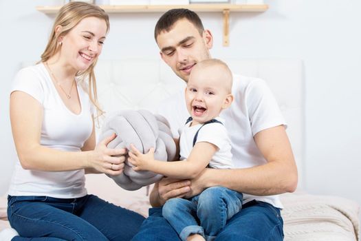 Mom, dad and little son are playing at home. Young family with a child.