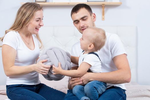 Mom, dad and little son are playing at home. Young family with a child.