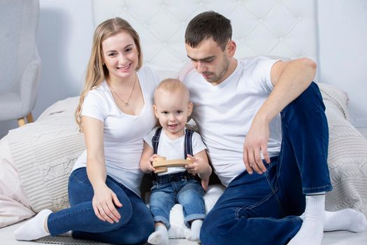 Mom, dad and little son are playing at home. Young family with a child.