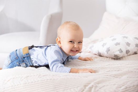 Funny child on the bed. A two year old boy smiles.