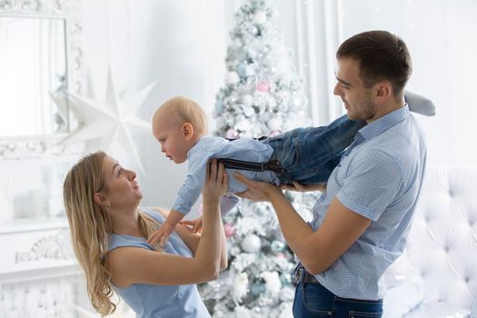 Family at Christmas. Mother father and child play against the background of a Christmas tree. Parents and son in the new year.