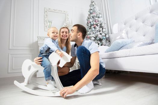 Family at Christmas. Mother father and child play against the background of a Christmas tree. Parents and son in the new year.