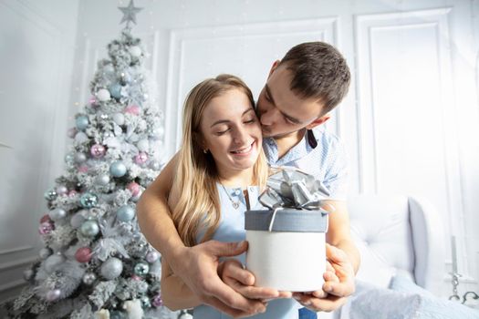 Man gives a woman a Christmas present.Family at Christmas. The husband gives his wife a Christmas present. Lovers on the background of the Christmas tree.