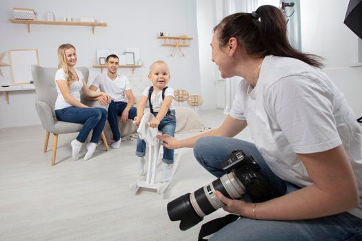 A photographer photographs a family in a photo studio.