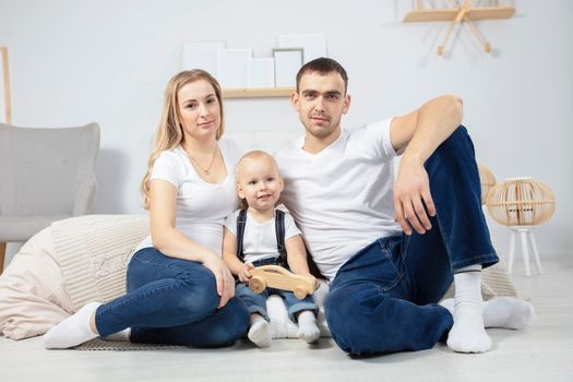 Family. Dad mom child sit on the floor at home. Portrait husband wife and little son. Couple with baby in the apartment