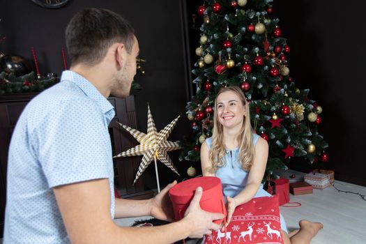 Family at Christmas. The husband gives his wife a Christmas present. Lovers on the background of the Christmas tree.