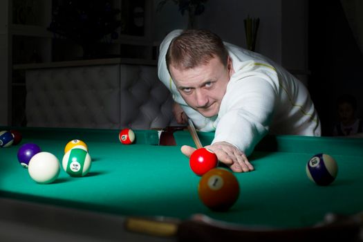 A man plays billiards. A man with a cue in his hands.