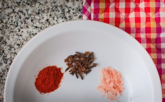 Paprika, clove and marine salt in a white dish. Top down view.