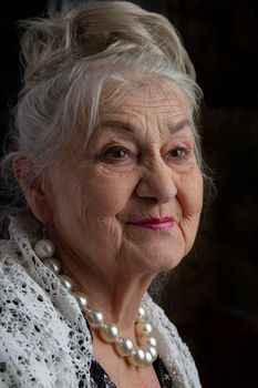 Portrait of a ninety year old woman. Beautiful old lady. Luxurious grandmother on a black background. Elderly beauty. The gray-haired well-groomed pensioner.