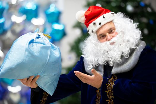 Santa Claus man points to a bag with a gift.Christmas holidays.