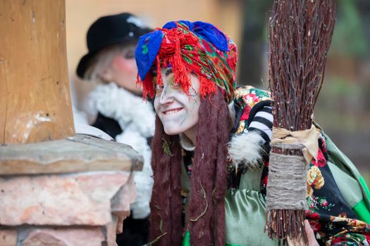 Baba Yaga with a broom near a wooden hut.