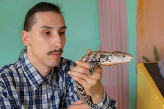 Belarus, the city of Gomel, August 15, 2017. City Terrarium. A man holds a lizard in his hand. Herpetologist.