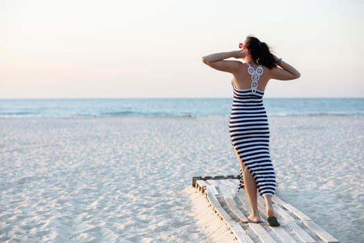 A woman goes to the sea along a sandy beach. Summer vacation on the ocean.