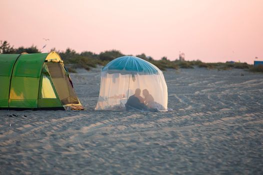 Relax on the beach in a tent. The coast and the silhouettes of people in the tent.