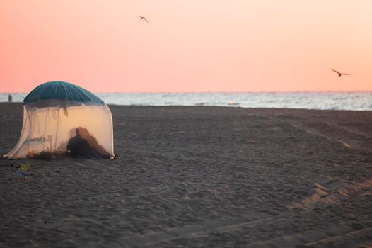 Relax on the beach in a tent. The coast and the silhouettes of people in the tent.