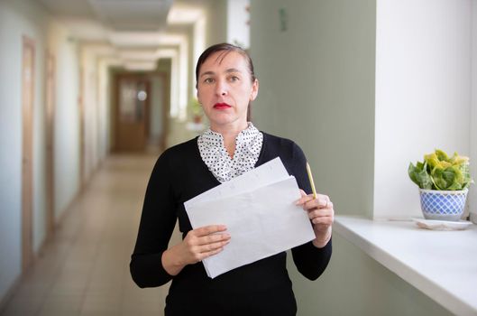 Woman with papers at the office. Co-worker in the hallway