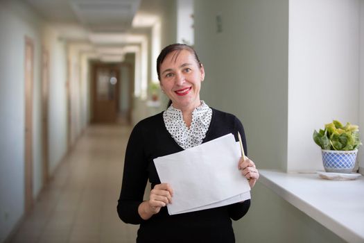 Happy woman at work. Female employee in the hallway with a piece of paper.