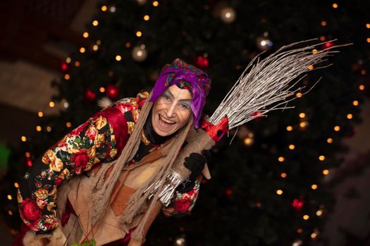 Baba Yaga with a broom on the background of the Christmas tree.Russian witch.