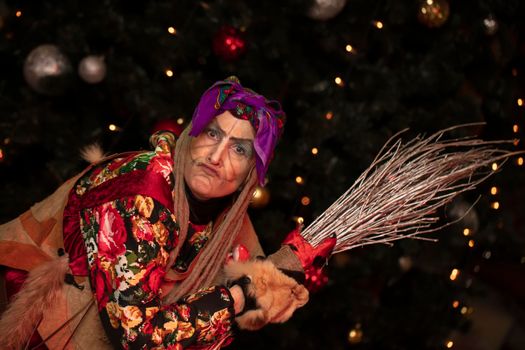 Baba Yaga with a broom on the background of the Christmas tree.Russian witch.