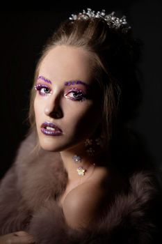 Luxurious girl with a beautiful make-up in a fur coat. Beauty in furs. Model on a dark background. Young beautiful woman.