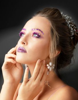 Model girl with bright makeup. Fashion makeup. Woman with violet restresses and eyebrows. Beautiful young face.