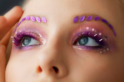 Female eyes with purple make-up. Beautiful extended eyelashes and eyebrows.