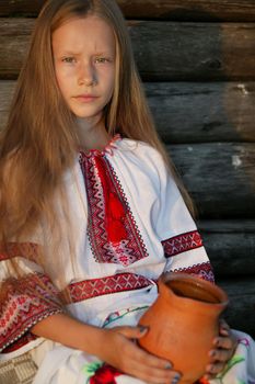 Slavic girl in an embroidered shirt with a clay jug. Ukrainian girl. The blonde in national dress.