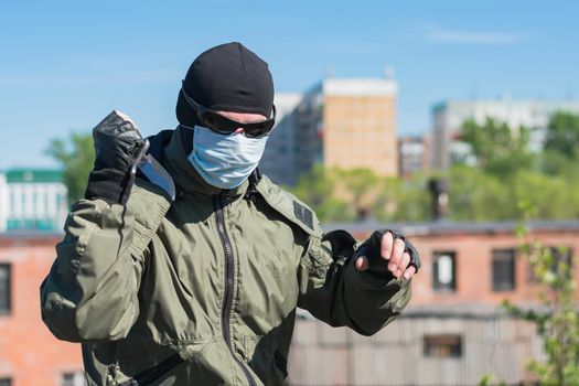 A man wearing a mask and glasses brandishes a knife in the street