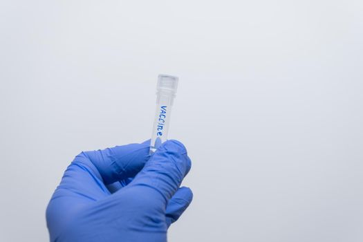 Close-up of a transparent test tube with a vaccine in the doctor’s hand.