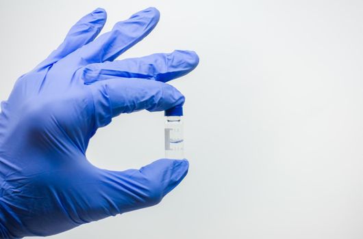The scientist holds the analogue of the vaccine with two fingers in a small test tube.
