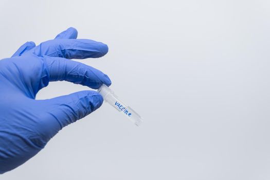 Doctor with gloved hand holds a bottle of vaccine for the upper part, close-up.