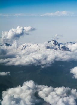 Mountain peaks in the clouds, top view, from the airplane. Clouds in the mountains.