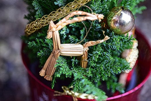 Close up of a straw horse at a small decorated christmas tree