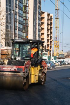 KYIV, UKRAINE - September 10, 2020: Heavy asphalt road roller with heavy vibration roller compactor that press new hot asphalt on the roadway on a road construction site on a street