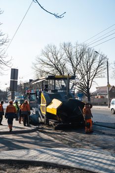 KYIV, UKRAINE - September 10, 2020: Heavy asphalt road roller with heavy vibration roller compactor that press new hot asphalt and asphalt paver machine on a road construction site on a street