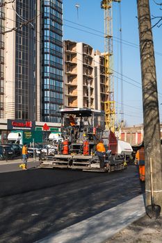 KYIV, UKRAINE - September 10, 2020: Industrial asphalt paver machine laying fresh asphalt on road construction site on the street