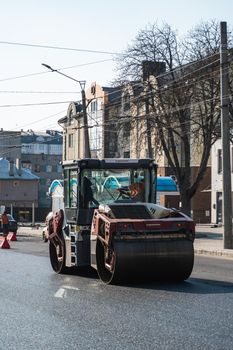 KYIV, UKRAINE - September 10, 2020: Heavy asphalt road roller with heavy vibration roller compactor that press new hot asphalt on the roadway on a road construction site on a street