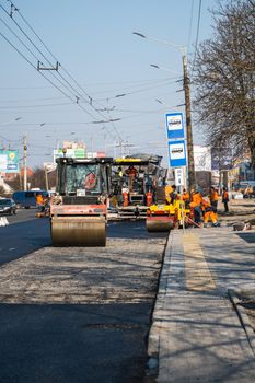 KYIV, UKRAINE - September 10, 2020: Heavy asphalt road roller with heavy vibration roller compactor that press new hot asphalt and asphalt paver machine on a road construction site on a street