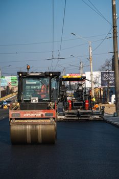 KYIV, UKRAINE - September 10, 2020: Heavy asphalt road roller with heavy vibration roller compactor that press new hot asphalt and asphalt paver machine on a road construction site on a street