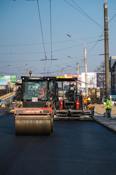 KYIV, UKRAINE - September 10, 2020: Heavy asphalt road roller with heavy vibration roller compactor that press new hot asphalt and asphalt paver machine on a road construction site on a street