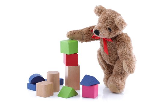 A cute teddy bear playing with toy wood blocks