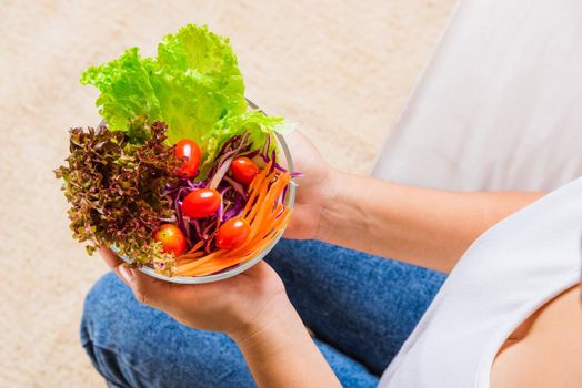 Female hands holding bowl with green lettuce salad on legs, Above young woman eating fresh salad meal vegetarian spinach in a bowl, Clean detox healthy homemade food concept