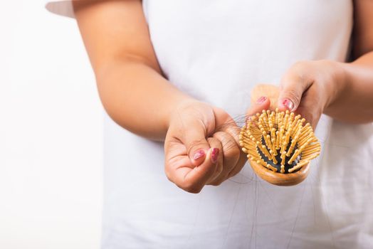 Asian woman unhappy weak hair problem her hold hairbrush with damaged long loss hair in the comb brush she pulls loss hair from the brush, isolated on white background, Medicine health care concept