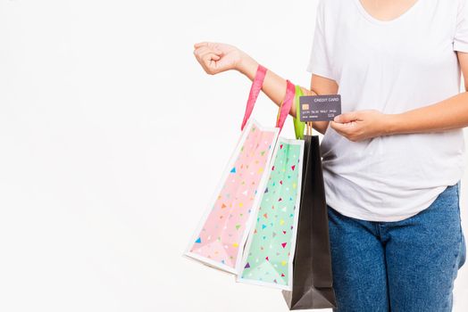 Closeup women hand holding colorful shopping bag many packets and credit card, studio shot isolated on white background, female holds in hand with clear empty blank craft paper gift bag for purchases