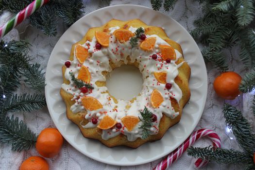Round Christmas dessert is decorated with tangerine slices on a white plate